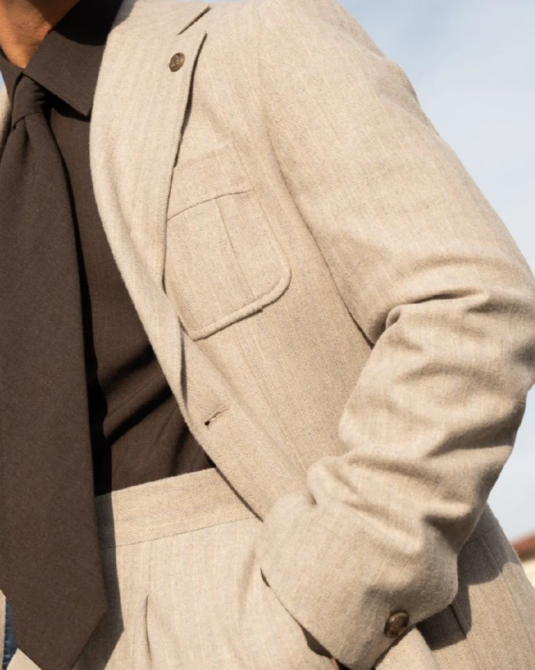 Faithful close crop of the original beige lapel, pocket and brown tie